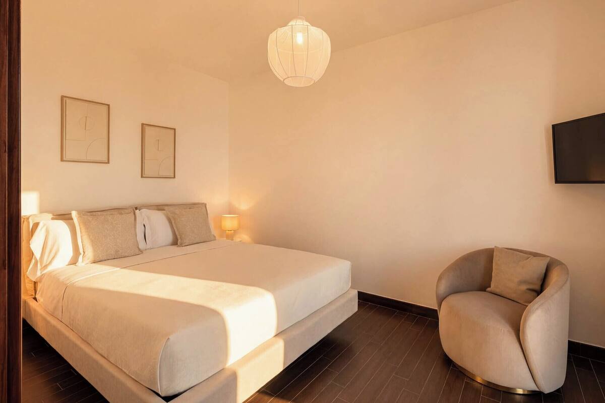 Une chambre d’hôtel moderne équipée d’un lit, de lampes de chevet, d’une chaise et d’un téléviseur.