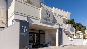 The exterior of the Arboris Belli Hotel with a modern design, featuring a prominent entrance, a balcony, and potted plants. - ARBORIS BELLI HOTEL  (Alberobello)