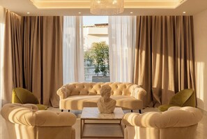 En elegant stue med sofa, to lænestole, et marmorbord og en buste.