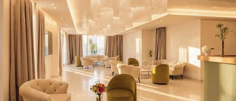 A spacious lobby with a modern chandelier, plush seating, and a reception desk.
