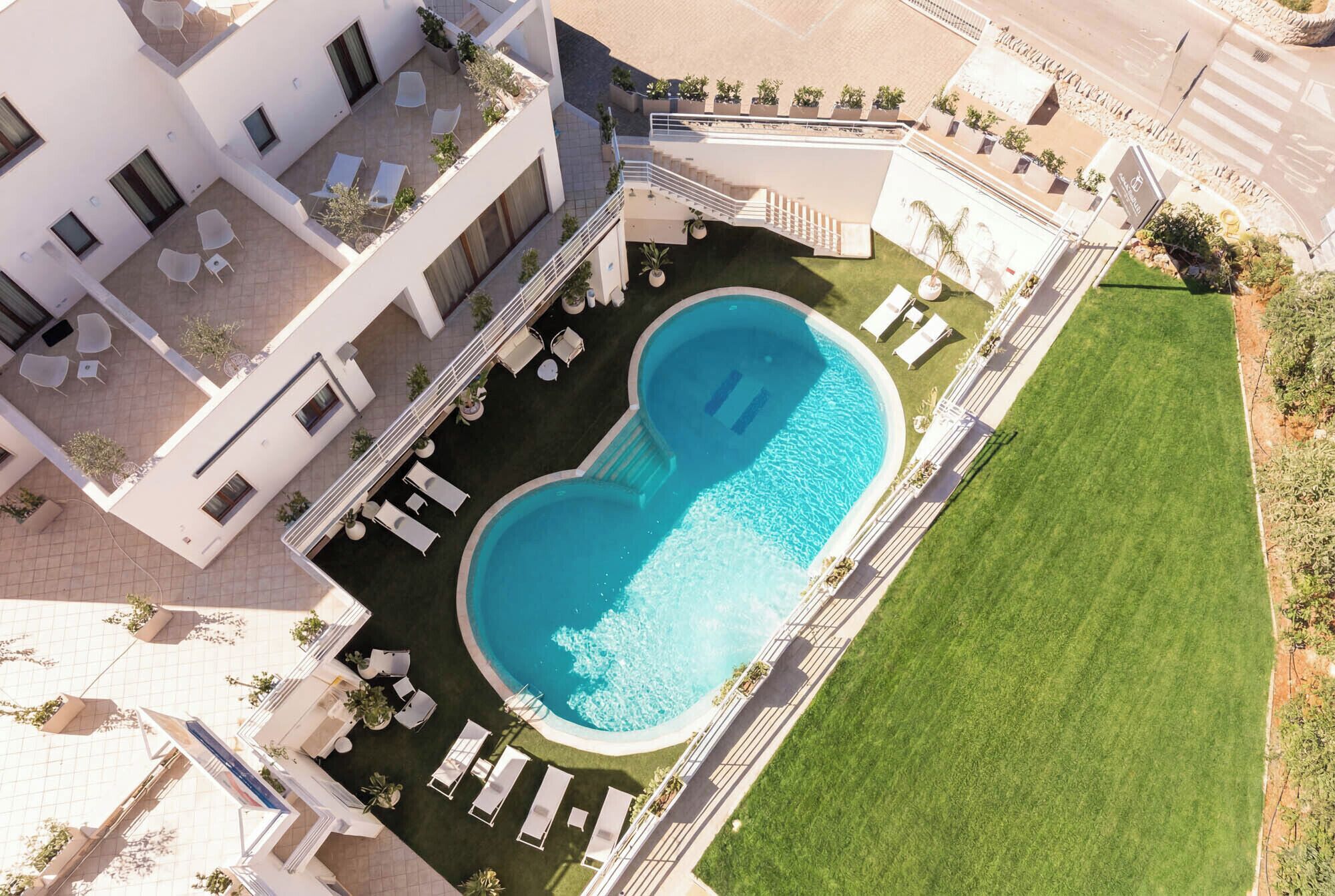 A modern hotel with a rooftop pool, outdoor seating, and a well-maintained lawn.