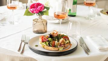 Una mesa de comedor con un plato de comida, copas de vino y cubiertos.