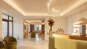 A modern hotel lobby with a reception desk, seating area, and large windows. - ARBORIS BELLI HOTEL  (Alberobello)