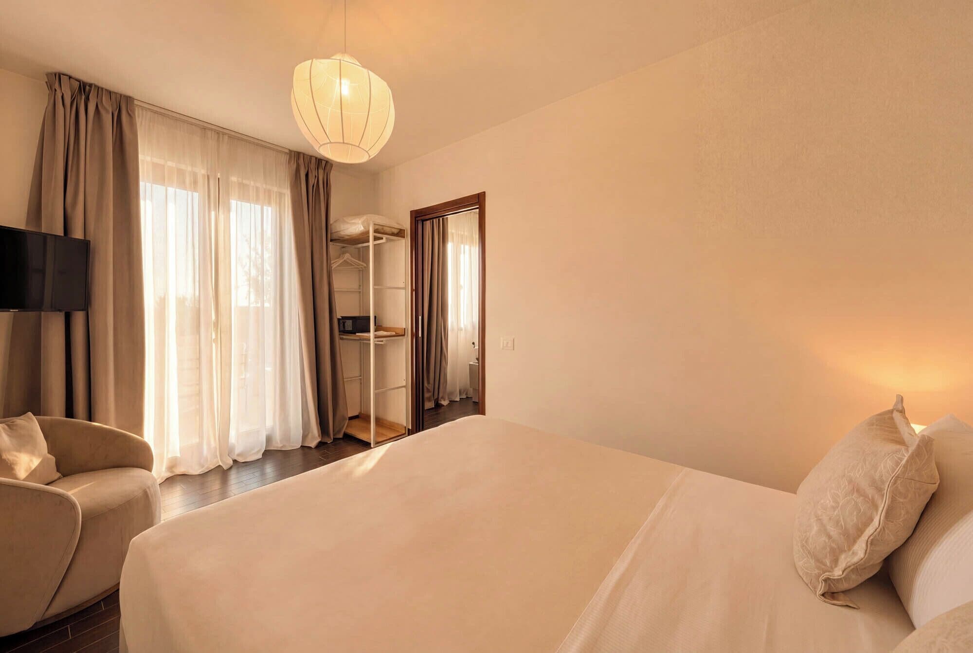 A hotel room with a bed, a TV, a wardrobe, and a mirror.