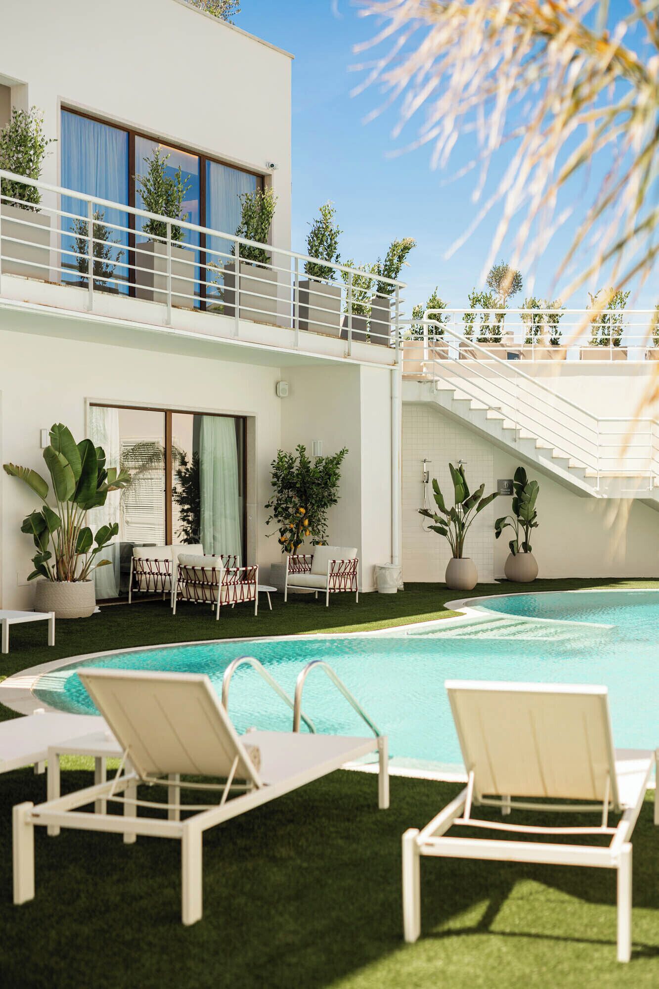 A pool area with lounge chairs, a staircase, and potted plants.