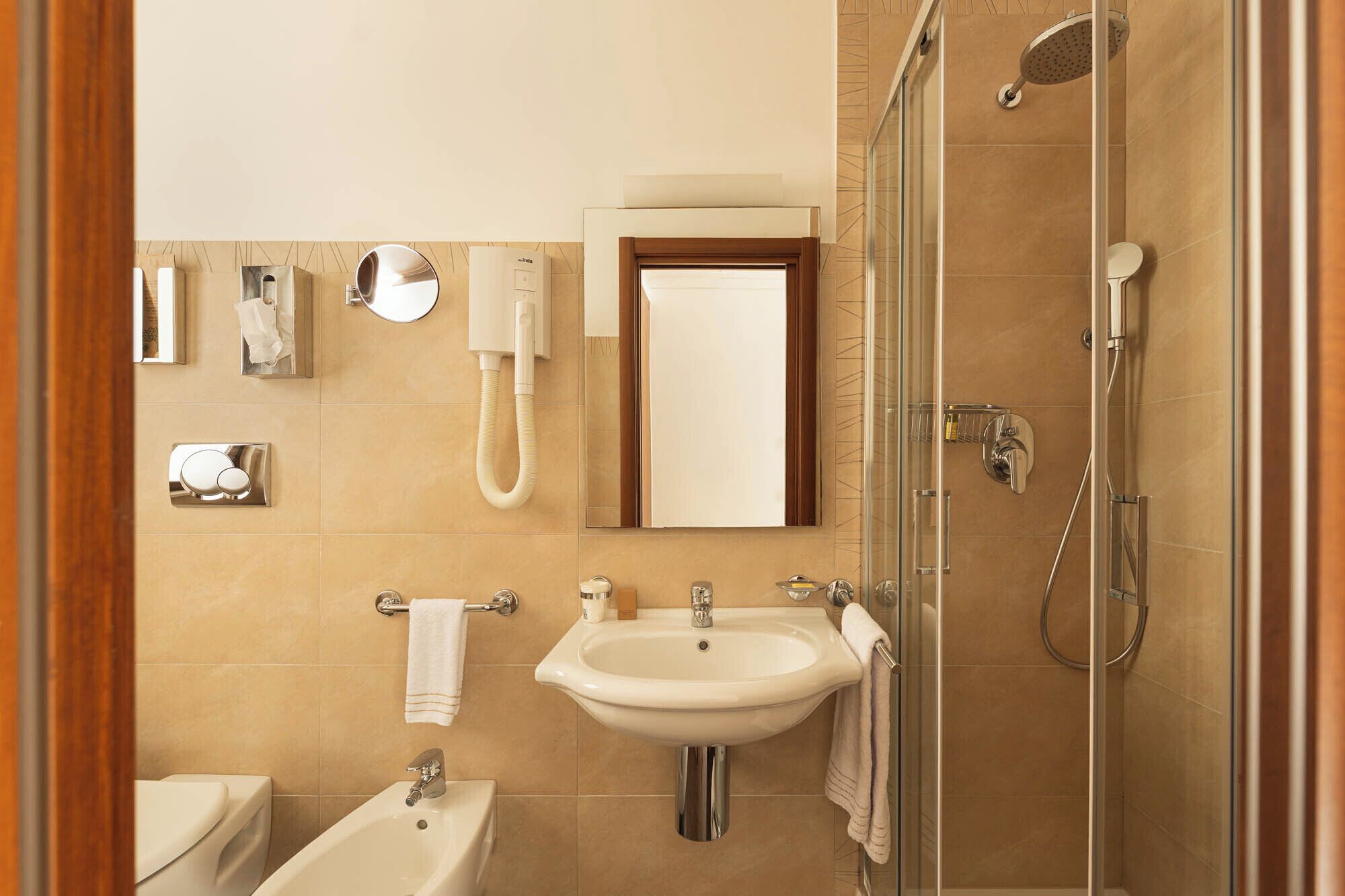 Un baño moderno con lavamanos, espejo, inodoro y ducha.