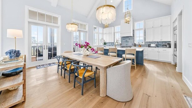 A spacious kitchen with white cabinets, a wooden dining table, and pendant lighting. - Bay Views, 3 King Suites & Ultimate Kids Retreat @CinnamonShore (Port Aransas)