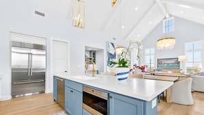 A modern kitchen with a large island, stainless steel appliances, and a view of the living area. - Bay Views, 3 King Suites & Ultimate Kids Retreat @CinnamonShore (Port Aransas)