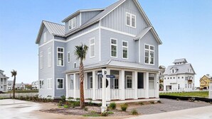 A two-story house with a porch, a palm tree, and a street sign. - Bay Views, 3 King Suites & Ultimate Kids Retreat @CinnamonShore (Port Aransas)