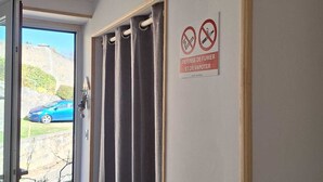 Ein Zimmer mit einer Schiebetür, einem Schild, das Rauchen und Dampfen untersagt, und Blick auf einen blauen Wagen vor dem Fenster.