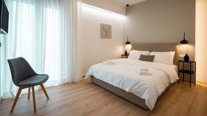 A modern bedroom with a bed, a chair, a bedside table, and a television. - THE EDGE Luxurious Penthouse Shared Gym (Kallithea)