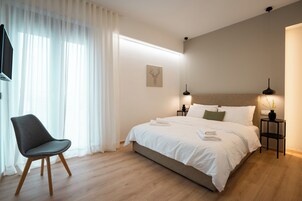 Un dormitorio moderno con cama, una silla, una mesita de noche y un televisor.