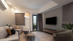 A modern living room with a sofa, armchair, coffee table, and a flat-screen TV mounted on the wall. - THE EDGE Luxurious Penthouse Shared Gym (Kallithea)
