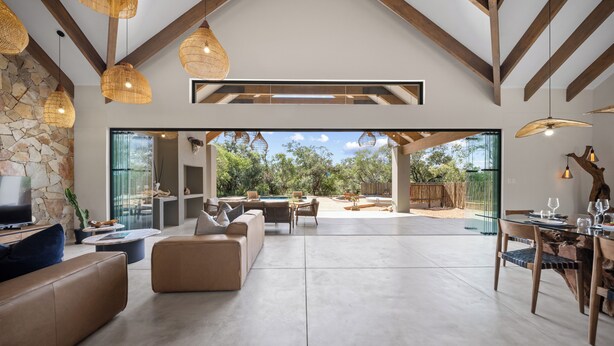 A spacious living area with a stone wall, modern furniture, and large windows. - Kimbilia Luxury Villa  (Hoedspruit)
