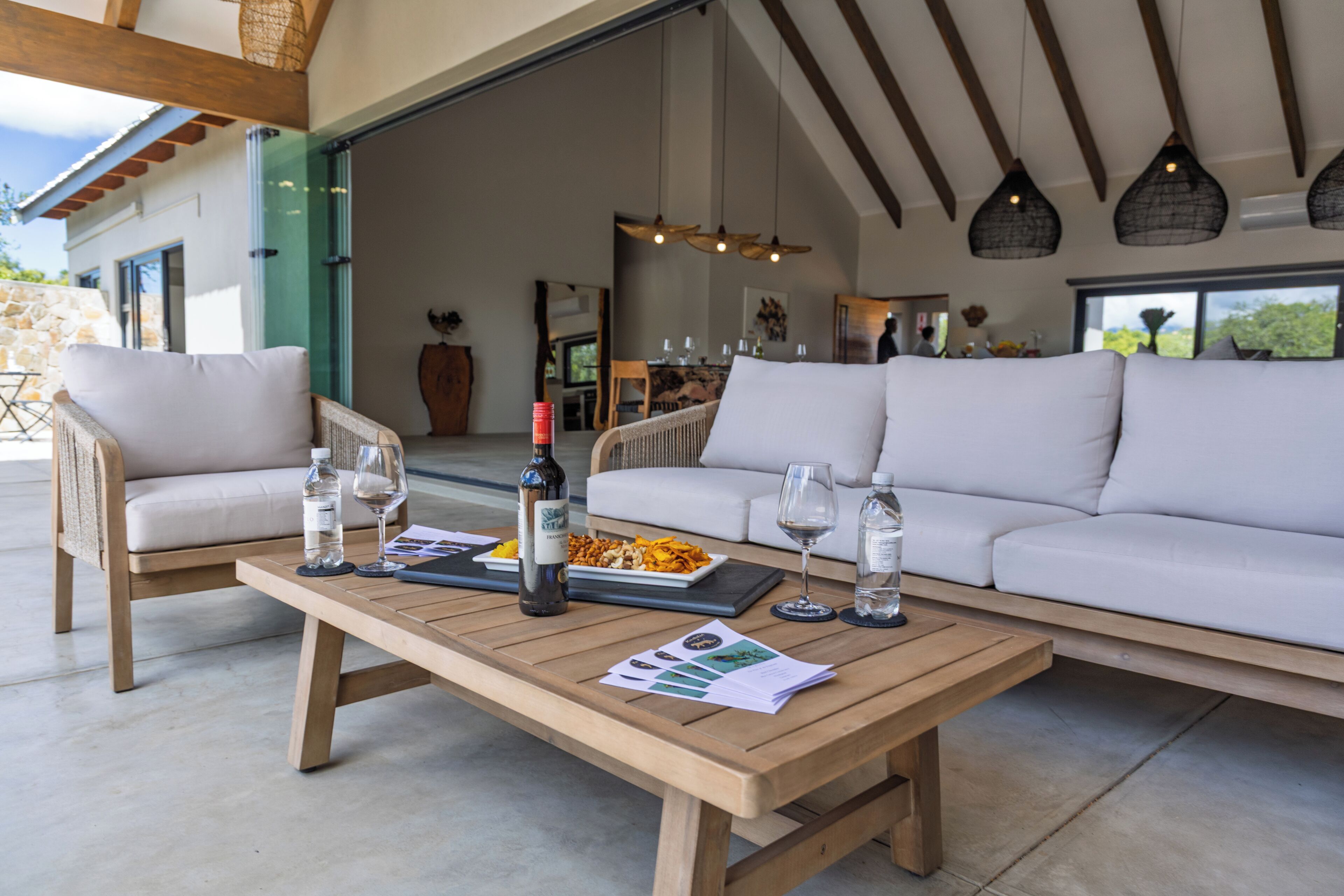 Un espace extérieur moderne, aménagé avec une table en bois, des chaises blanches dotées de coussins et un canapé.