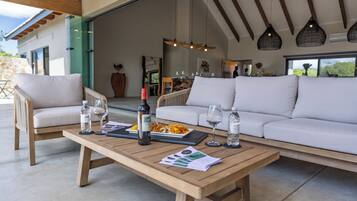 Un espace extérieur moderne, aménagé avec une table en bois, des chaises blanches dotées de coussins et un canapé.
