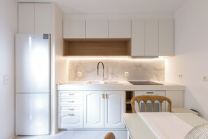 Une cuisine compacte avec des meubles blancs, un évier encastré et une table en bois.