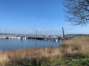 Un port de plaisance avec des bateaux amarrés, une jetée s’avançant dans l’eau et un ciel dégagé.
