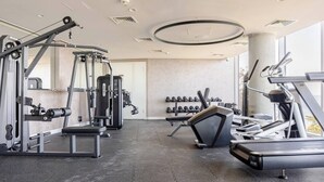 Et fitnesscenter med løbebånd, styrketræningsudstyr og håndvægte.