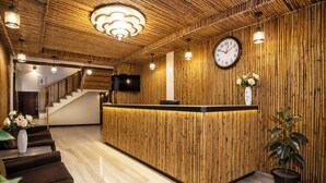 Ein Empfangsbereich mit einem Holzbüro, einer Uhr, einem Fernseher und einer Treppe zu einer anderen Etage.