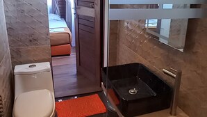 A bathroom with a toilet, a black sink, and a mirror. - Cozzy D'Sobahan Resort (Ngadirejo)