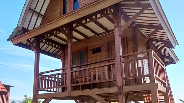 A wooden cabin with a balcony, a second-story deck, and a steeply pitched roof. - Cozzy D'Sobahan Resort (Ngadirejo)