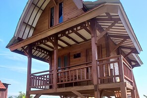 A wooden cabin with a balcony, a second-story deck, and a steeply pitched roof.