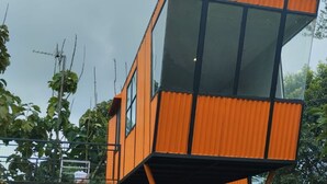 A modern, orange building with large windows and a unique angular design. - Cozzy D'Sobahan Resort (Ngadirejo)