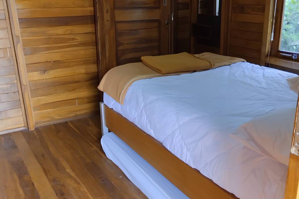 Ein holzgetäfeltes Zimmer im Chalet-Stil mit Bett, Holzwänden und einem Fenster.