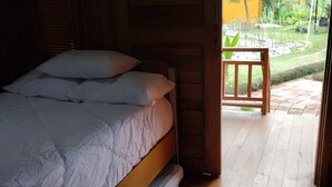 A bedroom with a bed, wooden walls, and a view of a garden. - Cozzy D'Sobahan Resort (Ngadirejo)