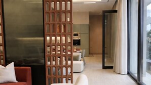 Een moderne woonkamer met een hoekbank, een witte salontafel en een houten scheidingswand.