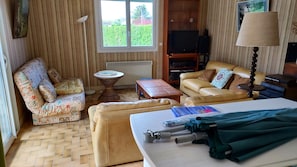 Une pièce comprenant un canapé, un fauteuil, une petite table et un lit avec des couvertures pliées.