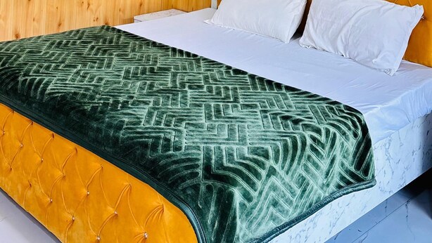 Una habitación con paneles de madera, una cama, un ventilador de techo y una lámpara fijada a la pared.