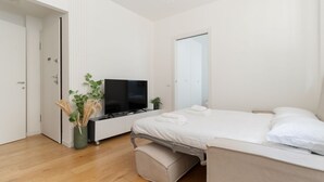 Une chambre à coucher moderne avec un lit, une télévision et une petite plante.