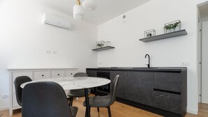 Une cuisine moderne avec un îlot en marbre, des chaises noires et un plan de travail noir.