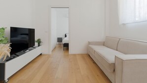 Un salon moderne avec un téléviseur à écran plat, un canapé, une table basse et une plante en pot.