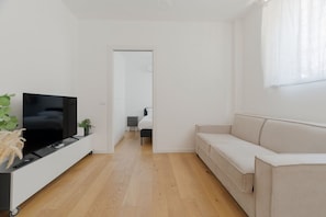 Un soggiorno moderno con una televisione a schermo piatto, un divano, un tavolino da caffè e una pianta in vaso.