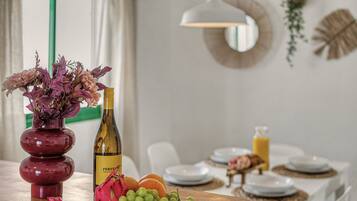 Een eettafel met een wijnfles, een fruitschaal en een bloevas.