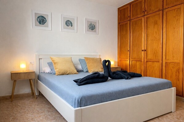 A bedroom with a bed, bedside tables, and a wardrobe.
