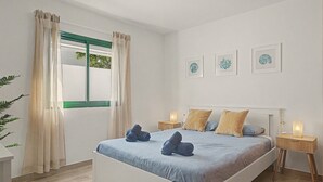 A bedroom with a bed, curtains, bedside tables, and wall art.