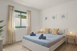 A bedroom with a bed, curtains, bedside tables, and wall art.