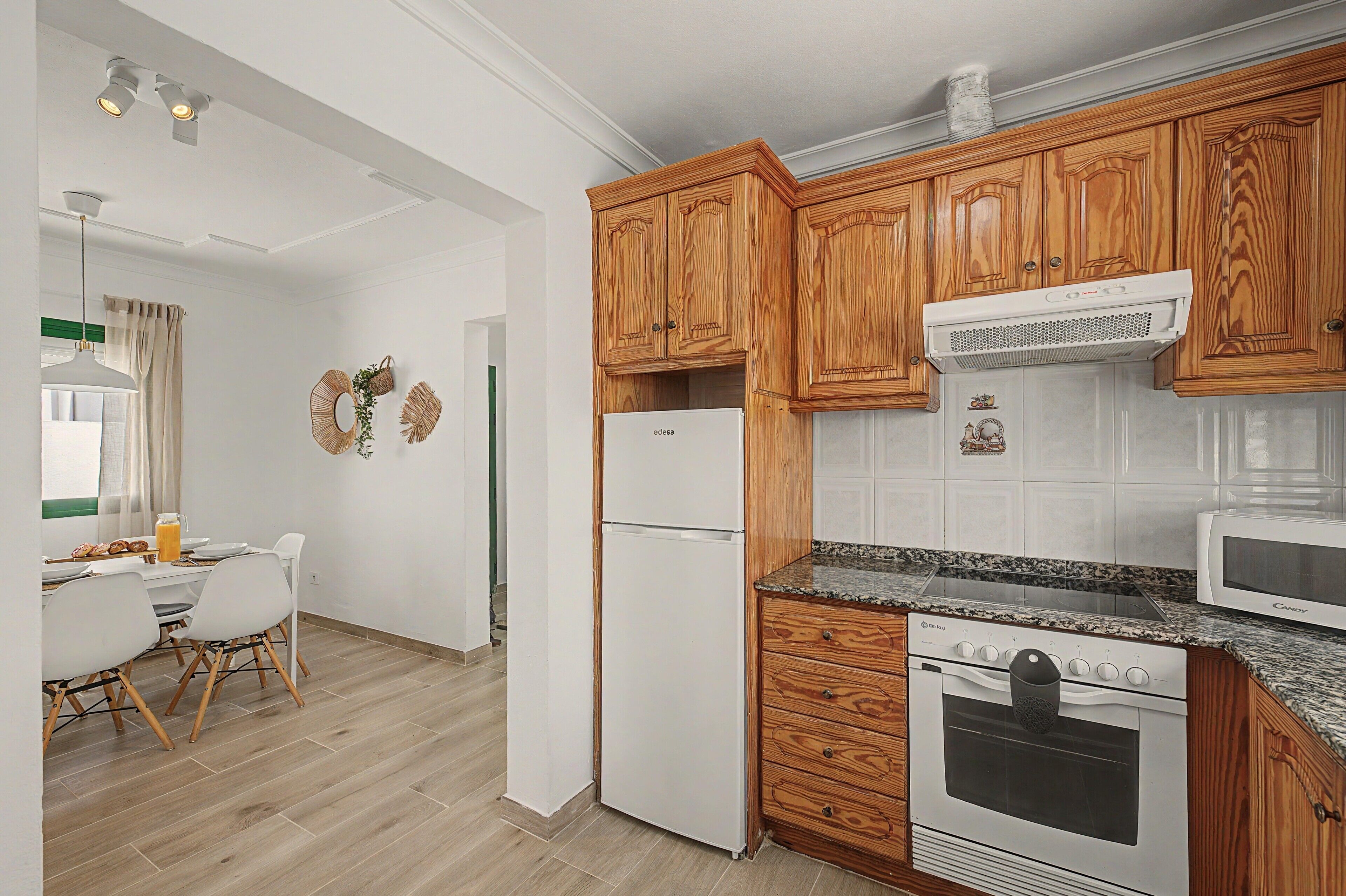 A modern kitchen with wooden cabinets, a white refrigerator, a microwave, and an oven.