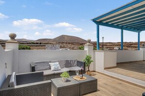 A rooftop terrace with a seating area, a pergola, and a view of a mountainous landscape. - Kalendra Jable – Quiet house near the sea in northern Lanzarote (Urbanización los Cocoteros)