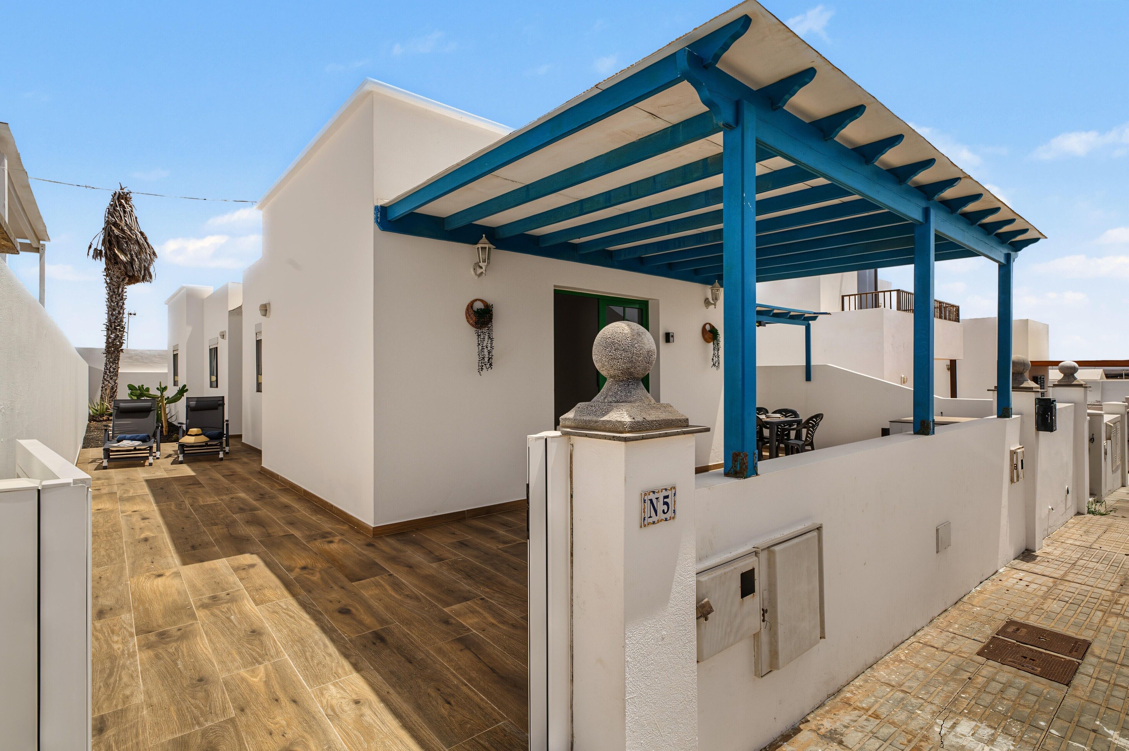 Edificio blanco con estructura de techo azul, suelo de madera y una puerta con la leyenda 'N5'.
