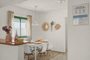 A modern kitchen with a dining area, a hanging pendant light, and a welcome sign. - Kalendra Jable – Quiet house near the sea in northern Lanzarote (Urbanización los Cocoteros)
