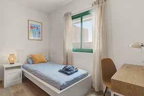 A small, neatly arranged bedroom with a single bed, a desk, a chair, and a bedside lamp. - Kalendra Jable – Quiet house near the sea in northern Lanzarote (Urbanización los Cocoteros)