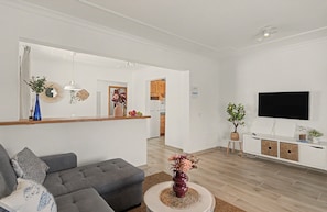 Una sala de estar moderna con un sofá gris, una mesa redonda de centro y un televisor de pantalla plana montado en la pared.