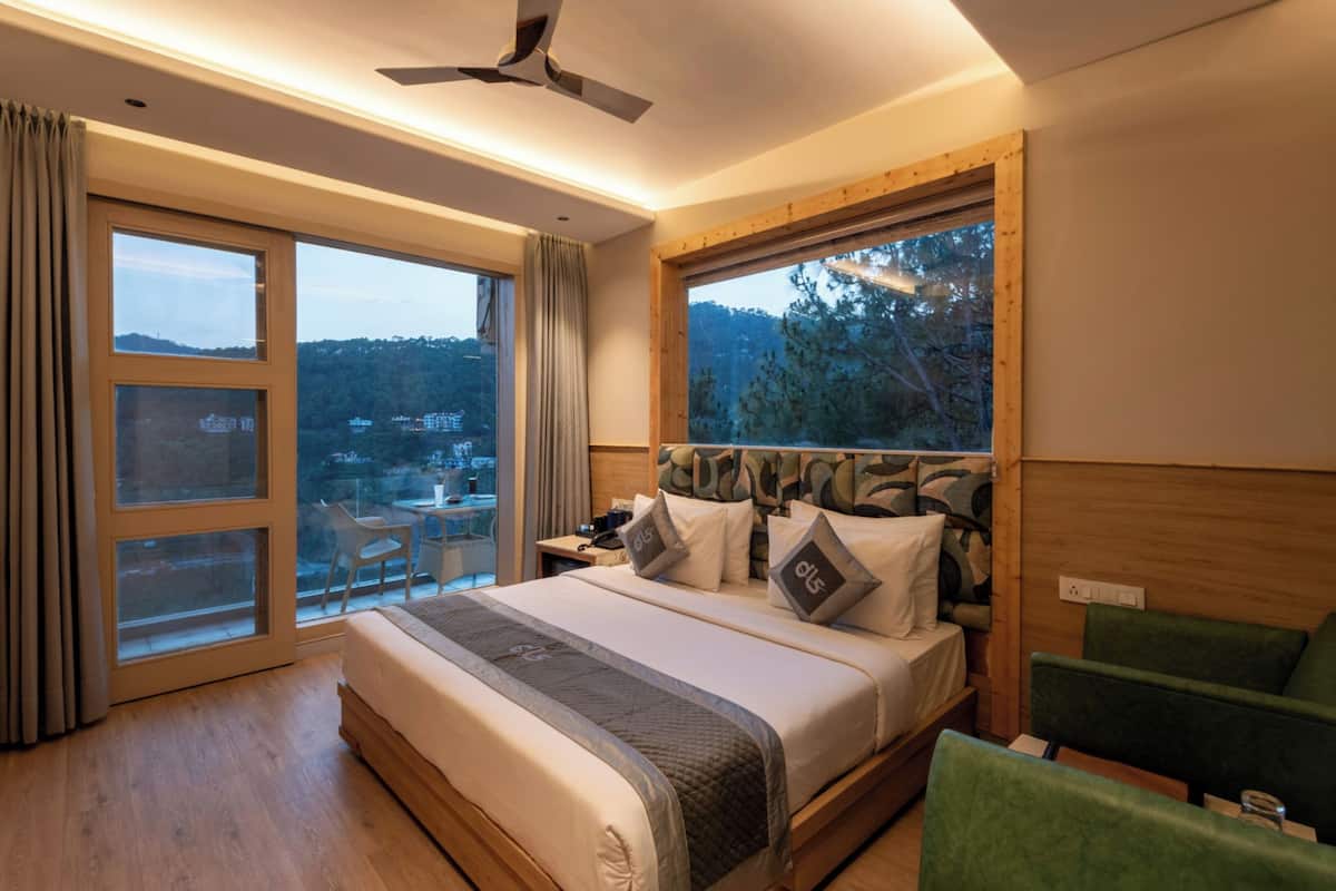Une chambre à coucher avec un grand lit, une table de chevet, une chaise et une vue sur l’extérieur grâce à de grandes fenêtres.
