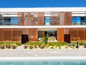 Ein modernes, zweistöckiges Gebäude mit Pool, Sitzgelegenheiten im Freien und einem gepflegten Garten.