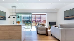 A modern living room with a sofa, a TV, and a dining area with a table and chairs. - Burgau Sea Garden - Apartment O0 (Budens)